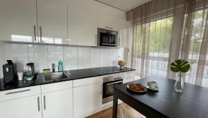 een keuken met witte kasten en een zwart aanrechtblad bij Modernes Luxus Apartment direkt neben Shopping und Bus in Schaan