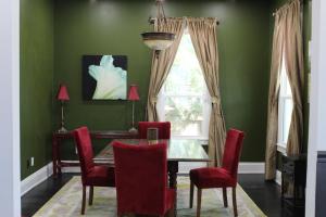 Un comedor con paredes verdes, una mesa y sillas rojas. en Historic Home Near UF Health & Stadium, en Jacksonville