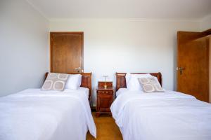 Dos camas en una habitación con sábanas y almohadas blancas. en The Valley View Guest House, en Melbourne