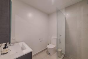 a white bathroom with a toilet and a glass shower at Modern Addington Escape Stylish 2br Townhouse in Addington