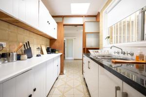Una cocina con gabinetes blancos y piso de baldosas. en The Valley View Guest House, en Melbourne 16 fotos más