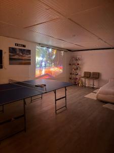 a ping pong table in a room with a large screen at Nice and Cozy! in Lincoln