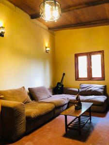 a living room with a couch and a table and a guitar at Gam Maduwa , cooking class and Tours in Nuwara Eliya