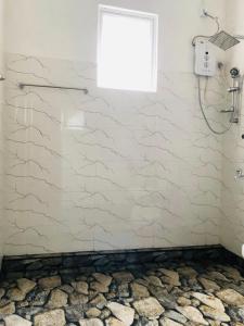 a bathroom with a shower and a stone wall at Gam Maduwa , cooking class and Tours in Nuwara Eliya