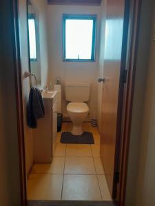 Un baño con inodoro, lavabo y ventana. en cliff top house guest rooms, en Whangaparaoa
