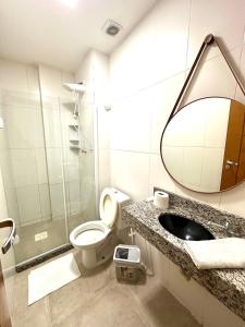 une salle de bain avec toilettes, lavabo et miroir dans l'établissement Eu Amo Arraial Hospedagem - Studio Sophia I Vista Mar, à Arraial do Cabo