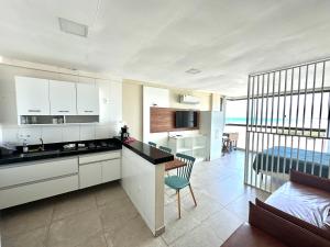 une cuisine avec des armoires blanches, une table et un canapé dans l'établissement Eu Amo Arraial Hospedagem - Studio Sophia I Vista Mar, à Arraial do Cabo