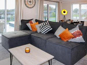 a living room with a black couch with colorful pillows at 38 At The Sanctuary Lodges - Uk50850 in Carnguwch