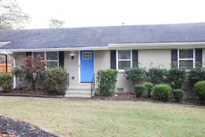 een wit huis met een blauwe deur en struiken bij Family Fun Vibe in Marietta