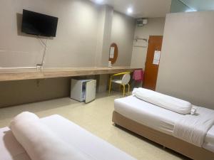 ein Zimmer mit zwei Betten und einem Schreibtisch mit Fernseher in der Unterkunft Lithai Guesthouse in Phitsanulok