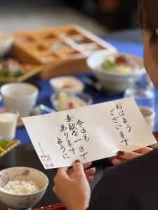 een persoon die een stuk papier omhoog houdt met daarop geschreven bij オーベルジュ鈴鐘 in Koriyama