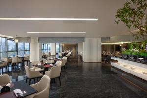 南昌市にあるRadisson Blu Hotel Nanchangのテーブルと椅子と窓のあるレストラン