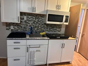 a kitchen with white cabinets and a sink and a microwave at Gull lake in Winnipeg