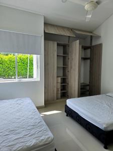 1 Schlafzimmer mit 2 Betten, einem Fenster und Regalen in der Unterkunft Casa de Descanso con Piscina y Jardín Ricaurte in Ricaurte + 17 Fotos