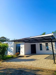 ein weißes Haus mit einem Walmdach in der Unterkunft Casa de Descanso con Piscina y Jardín Ricaurte in Ricaurte