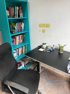 een zwart bureau met een stoel naast een boekenplank bij Stúdio Viajante in Barcarena