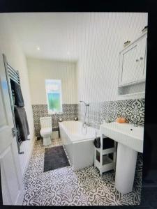 a bathroom with a tub and a toilet and a sink at Newcastle Pet friendly 1 bed drive garden 10m city in Kenton