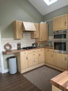 a kitchen with wooden cabinets and a stove top oven at Newcastle Pet friendly 1 bed drive garden 10m city in Kenton +3 photos