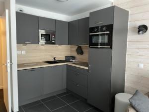 a kitchen with gray cabinets and a sink and microwave at Gourette - Duplex 8 pers, 60 m², animaux admis - FR-1-860-10 in Gourette +4 photos
