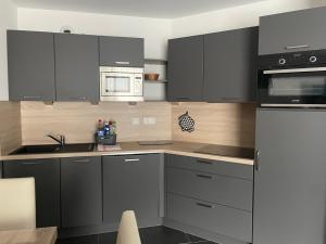 a kitchen with black cabinets and a white microwave at Appartement spacieux pour 8 personnes à Gourette avec piscine et animaux acceptés - FR-1-860-18 in Gourette