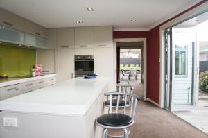 ニュープリマスにあるRelax on Richmond - modern beachside house retreatのキッチン(白いカウンター、スツール付)