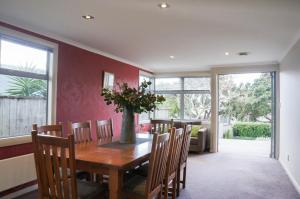 ニュープリマスにあるRelax on Richmond - modern beachside house retreatのダイニングルーム(テーブル、椅子、花瓶付)