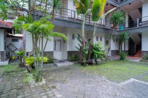 a courtyard of a building with trees and plants at Urbanview Hotel Wayan Mansion in Denpasar