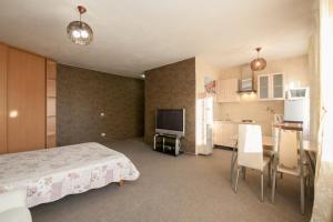 a bedroom with a bed and a table and a kitchen at Kvartirov Apartment at K.Marksa in Krasnoyarsk