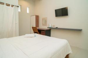 a bedroom with a bed and a desk with a television at Urbanview Hotel Wayan Mansion in Denpasar +32 photos