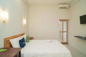 a bedroom with a white bed and a desk at Urbanview Hotel Wayan Mansion in Denpasar
