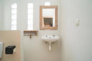 a bathroom with a sink and a mirror at Urbanview Hotel Wayan Mansion in Denpasar
