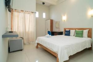 a bedroom with a large bed and a television at Urbanview Hotel Wayan Mansion in Denpasar