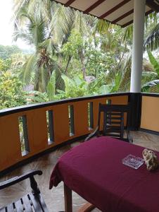 a balcony with a table and a view of a palm tree at freedom house in Unawatuna +42 photos