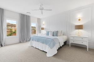 a white bedroom with a bed and a window at Farmhouse Hunter Valley in Pokolbin
