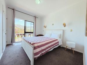 a bedroom with a bed and a large window at Cosy 6BR & 6BA Redwoods Lodge upto 14 People in Rotorua