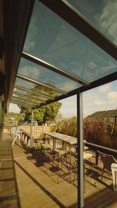 a wooden deck with tables and chairs and windows at Cosy 6BR & 6BA Redwoods Lodge upto 14 People in Rotorua