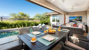 a patio with a table and chairs and a pool at PUALANI VILLA Single Level 4BR KaMilo Home with Pool and Cottage in Waikoloa