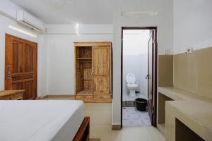 a bedroom with a bed and a bathroom with a toilet at Soka Asri Guest House near Bali Zoo RedPartner in Darmasaba