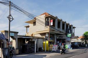 a man riding a motorcycle down a street next to a building at Soka Asri Guest House near Bali Zoo RedPartner in Darmasaba +1 photo