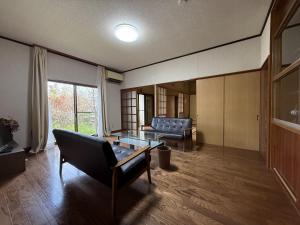 una sala de estar con un sofá y una mesa en 館山市犬石戸建 自然に囲まれた森のコテージ 6DK 最大18名宿泊可 パーティー BBQ 花火ok, en Tateyama