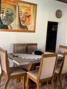 ein Esstisch mit Stühlen und ein Gemälde an der Wand in der Unterkunft Casa Sun and Sea in Salinópolis