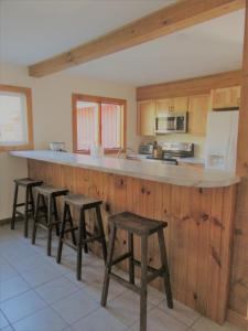 a kitchen with wooden cabinets and a counter with stools at Charming Cabin Retreat in the Foothills of the Adirondacks in Fort Ann, New York in Fort Ann