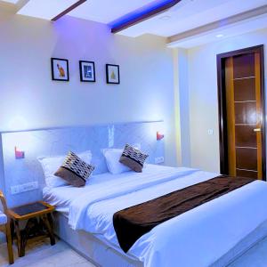 a bedroom with a large white bed and a chair at Cassava Stay close to Visa Center in New Delhi