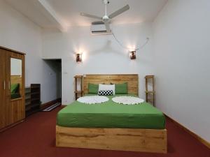 Schlafzimmer mit einem großen grünen Bett und einem Deckenventilator in der Unterkunft River Resort by The Ceylon Adventure Sports Kithulgala in Kitulgala