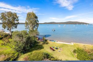 a view of a lake with people sitting on the grass at Zahirs Retreat in North Arm Cove