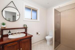 een badkamer met een toilet, een wastafel en een spiegel bij Zahirs Retreat in North Arms Cove