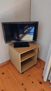 Ein Flachbildfernseher steht auf einem Holzständer. in der Unterkunft イザリCafe in Yokoo