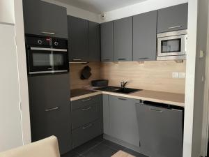 a kitchen with black and white cabinets and a sink at Studio à Gourette pour 4 pers, 29m² avec terrasse et piscine - FR-1-860-56 in Gourette