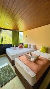 two beds in a room with a large window at Ella Deck Villa in Ella