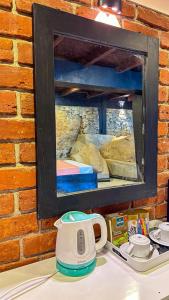 a mirror hanging on a brick wall with a tea kettle at Ella Deck Villa in Ella